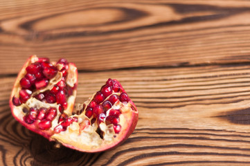 One broken half of red ripe fresh pomegranate on old brown weathered rustic planks