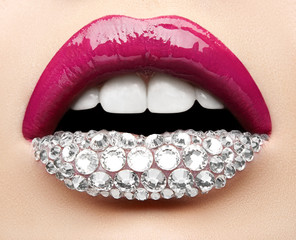 Naklejka premium Macro and close-up creative make-up theme: beautiful female lips with pink lipstick, white diamonds and teeth, retouched photo