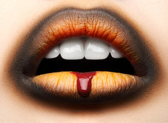 Macro and close-up creative make-up theme: beautiful female lips with black and orange lipstick and...