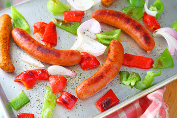 Overhead view of sheet pan meal of sausages, Overhead view of sheet pan meal of sausages, onions and bell peppers with dishcloth