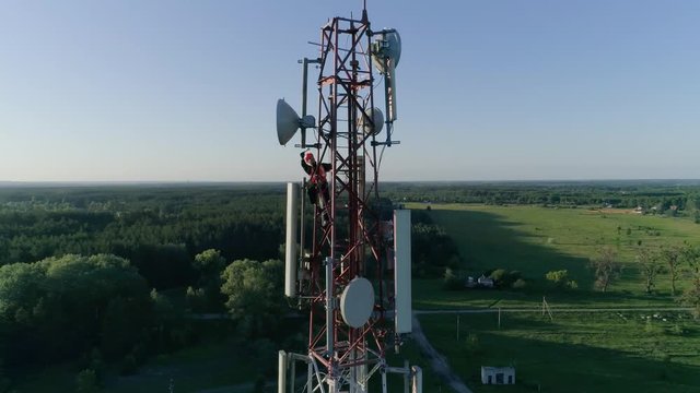 Maintenance personnel on cellular antenna at telecommunication tower