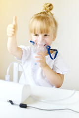 Little girl in a mask for inhalations, making inhalation with nebulizer at home inhaler on the...