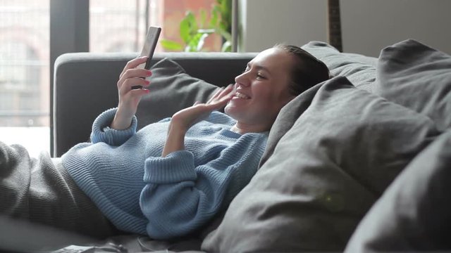 Young woman holding a smartphone during a skype video call with her friend
