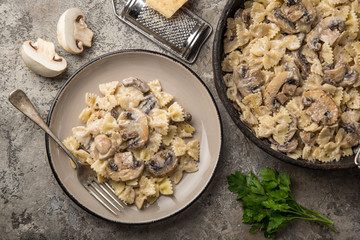 farfalle pasta with champignon mushrooms and garlic creamy sauce on pan