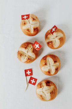 Swiss bread buns called in German 1. Augustweggen baked in Switzerland to celebrate Swiss National Day on August 1st. Swiss flag with white cross on red background.  White background, isolated.