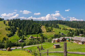 Beautiful countryside with neat rural houses standing on different sides of the road and farms with already cleaned and still lying dry hay.