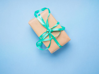 Wrapped gift with ribbon on blue pastel background. Giving presents concept