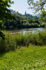 Mountain river, bright green bushes and trees against the backdrop of a church in the mountains create an incredibly beautiful natural portrait