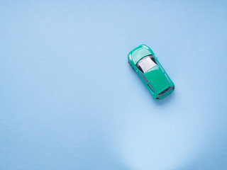 Green toy car on abstract blue background. Travel, purchase minimal concept