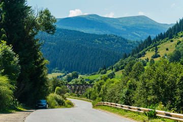 A winding road against the backdrop of a mountain slope with green trees
