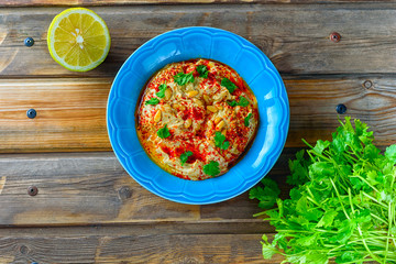 Chickpea hummus and tahini topped with pine nuts,olive oil, pepper, parsley, spices on a rustic wooden table. Hummus Traditional Middle Eastern food commonly served in a pita.
