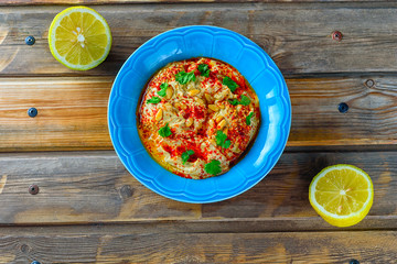Chickpea hummus and tahini topped with pine nuts,olive oil, pepper, parsley, spices on a rustic wooden table. Hummus Traditional Middle Eastern food commonly served in a pita.