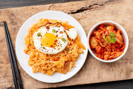 Kimchi fried rice with fried egg on top and fresh kimchi cabbage in a bowl, top view, Korean food