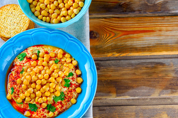 Hummus and tahini with olive oil, pepper, Chickpea, parsley, spices served in a cracker on a rustic wooden table.Hummus Traditional Middle Eastern food.