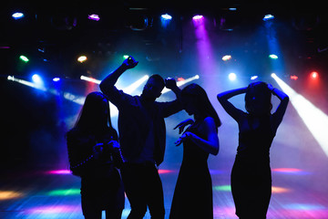 Young happy people are dancing in club. Nightlife and disco concept.