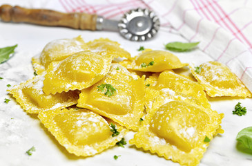 Ravioli pasta, homemade pasta and pasta roller on a stone background. Italian cuisine, fresh pasta cooking.