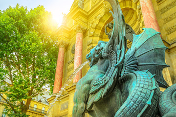 Spotted dragon at sunset light with Fontaine Saint-Michel on blurred background. The fountain is...