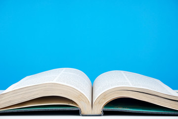 Education concept. An old book, eyeglasses over blue background