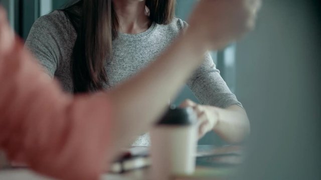 Tilt up beautiful young european woman with dark long hair female team leader in glasses sits at modern office desk and makes notes creative business team meeting and brainstorming in start up office