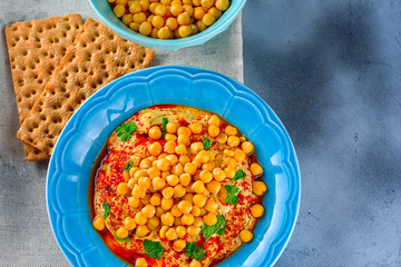 Hummus and tahini with olive oil, pepper, Chickpea, parsley, spices served in a cracker on a modern trendy background.Hummus Traditional Middle Eastern food. Copy space for text.