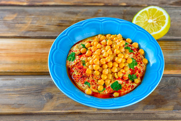 Hummus and tahini with olive oil, pepper, Chickpea, parsley, spices on a rustic wooden table.Hummus Traditional Middle Eastern food commonly served in a pita.