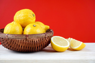 Selective focus. A close up of a fresh lemon inside a wooden basket over red background