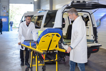 Fototapeta premium Paramedics wheeling empty stretcher to vehicle