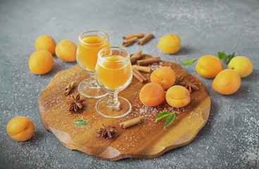 Spicy apricot liqueur in the glasses. Fresh apricots, cinnamon and anise on a wooden tray