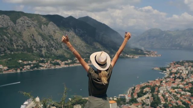 a woman reaching the goal on top with a view of the mountain bay