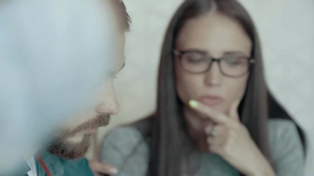 European man with beard and mustache attentively concentratedly listened female team leader in glasses creative business meeting and brainstorming in modern start up office teamwork discussing project