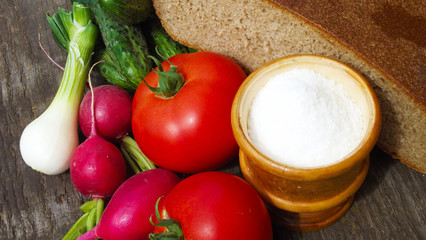 Fresh vegetables and rye bread on wooden background.