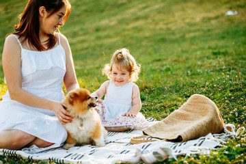 Mother and daughter in park with dog smiling. Sunset. Horizontal photo