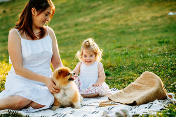 Mother and daughter in park with dog smiling. Sunset. Horizontal photo