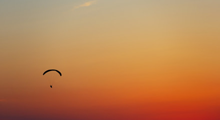 Man flight on a paraglider in a cloudless sky at sunset.