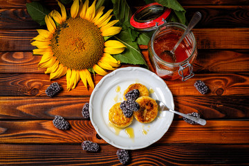 Breakfast.  pancakes made of cottage cheese with honey decorated with berries and sunflowers on a wooden background