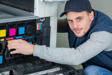 Man changing ink cartridges in photocopier