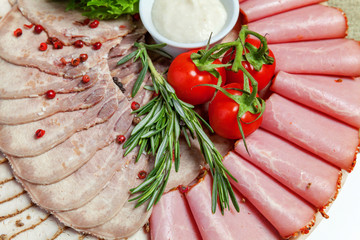 Board with different types of meat and ham delicacies, sauce and fresh vegetables. Restaurant menu assorted plate
