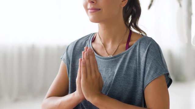 mindfulness, spirituality and healthy lifestyle concept - woman meditating at yoga studio