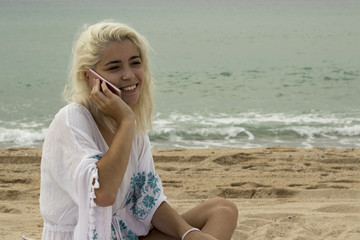 Smiling lady talking on the phone on the beach