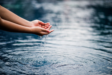 The hand that touches the blue water. The pool is clean and bright. With a drop of water on the...