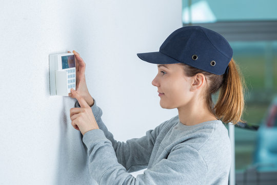 young female technician installing security system