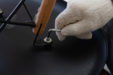 Close-up shot, hand of carpenter screwing path of chairs with hex key - 213268280