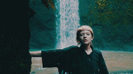 Beautiful fashion girl posing in tropical rain forest jungle near the waterfall. Portrait of...