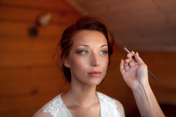 Process of making makeup. Make-up artist working with brush on model face. Portrait of young...