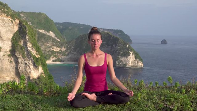 Yoga woman. Lotus pose on Kelingking beach cliff, Nusa Penida, Indonesia