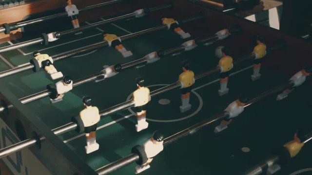 People playing in table football or kicker with miniature players. Table football game with yellow and white players. Employees playing table soccer indoor-game in the office during break time.
