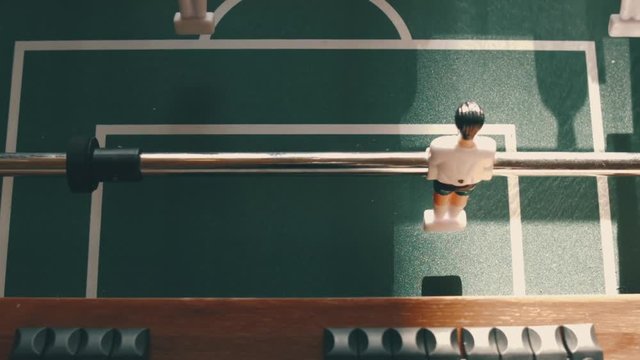 People playing in table football or kicker with miniature players. Table football game with yellow and white players. Employees playing table soccer indoor-game in the office during break time.