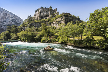 The river Sorgue in Fontaine de Vaucluse in the background the castle ruins from Philp Cabassole. Vaucluse, Provence, France, Europe - obrazy, fototapety, plakaty