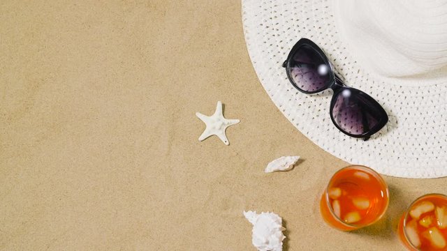 vacation, travel and summer concept - two glasses of aperitif cocktails, sun hat, sunglasses and seashells on beach sand