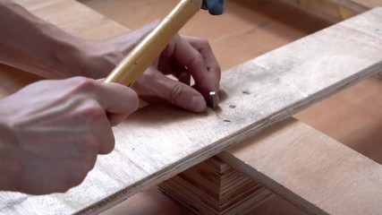 Hammering steel nail into wooden board